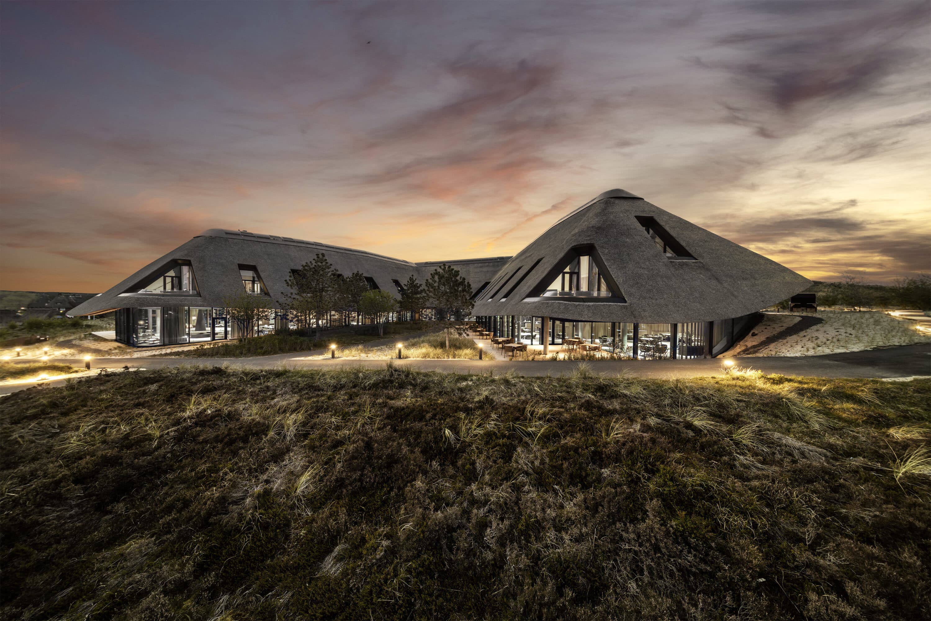 The building of Lanserhof Sylt with partly cloudy sky in the background with sunset colours