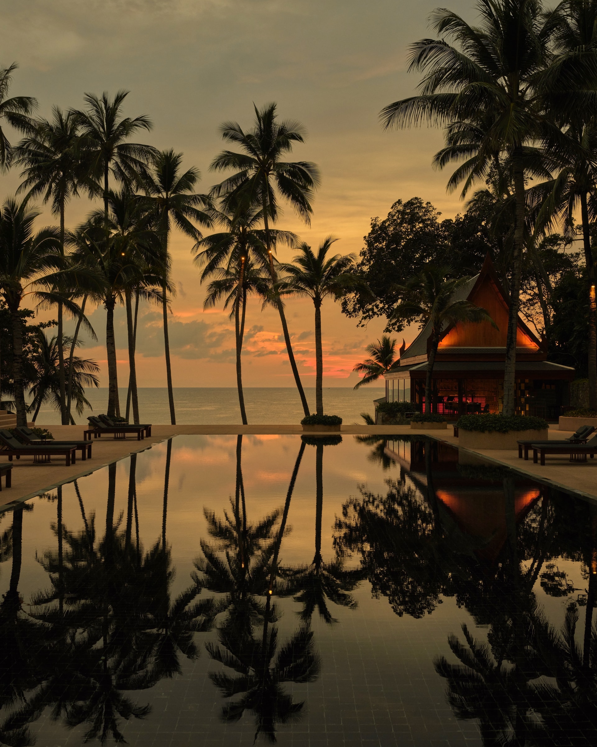 The black granite main pool at Amanpuri at sunset, the first Aman resort, on a private peninsula on Phuket’s west coast