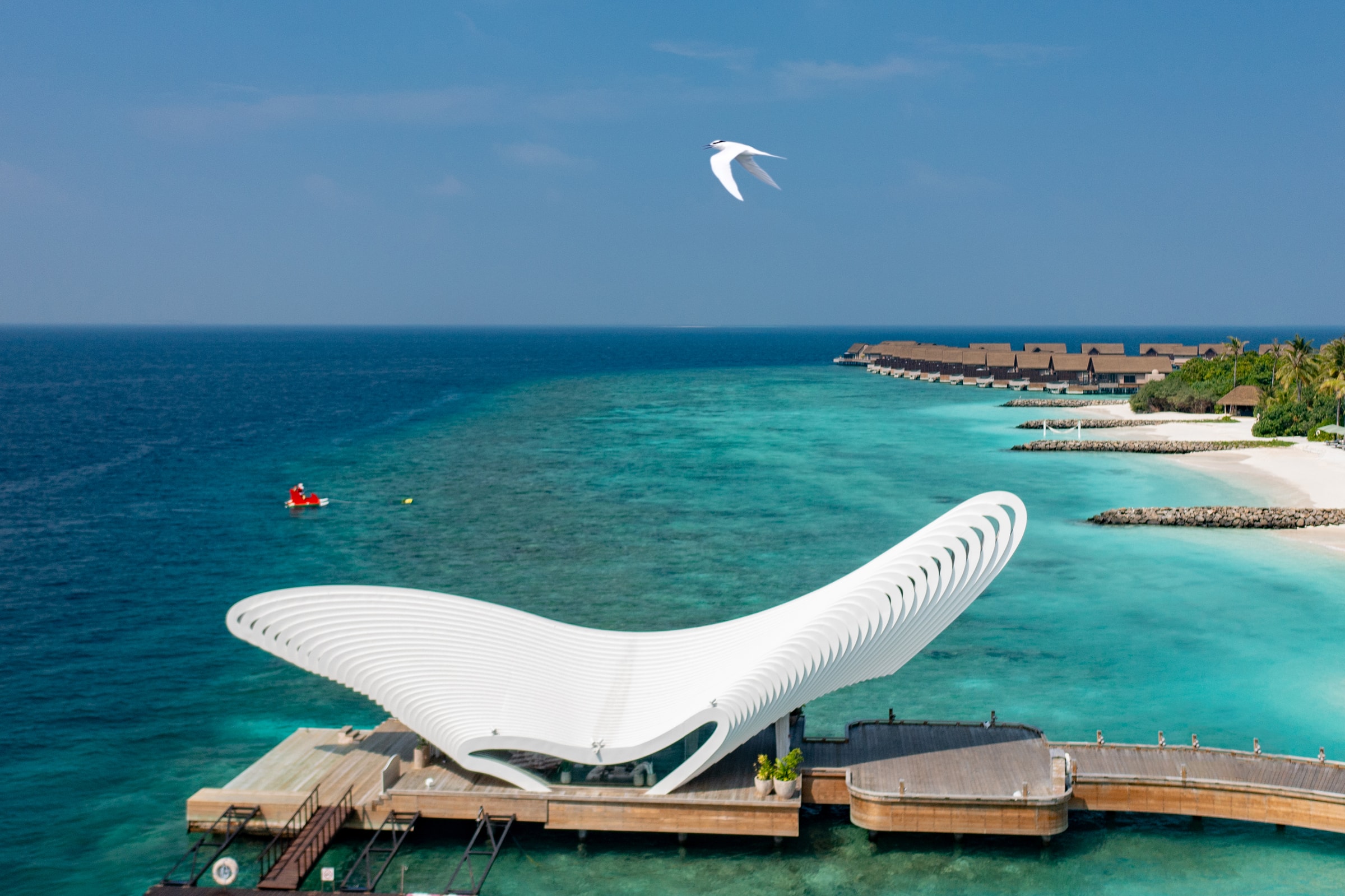 The sculptural arrival jetty at JOALI BEING over the turquoise lagoon, the first wellbeing island in the Maldives, Raa Atoll
