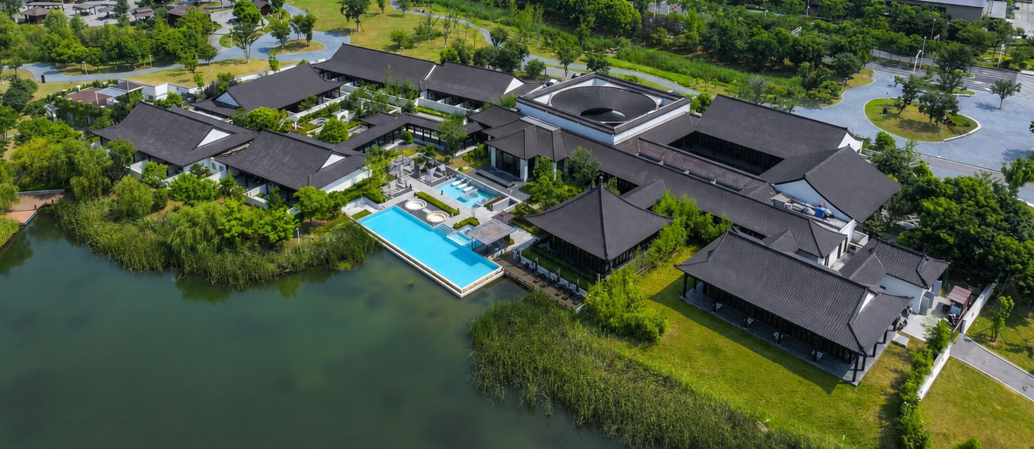 Ruihe Chiva Nanjing from the air, black tiled roofs around planted courtyards with the pool deck reaching out over the lake